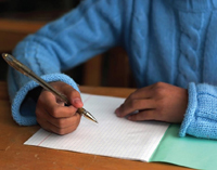 child writing at desk, view of hands only