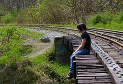 Person sitting next to railroad tracks.