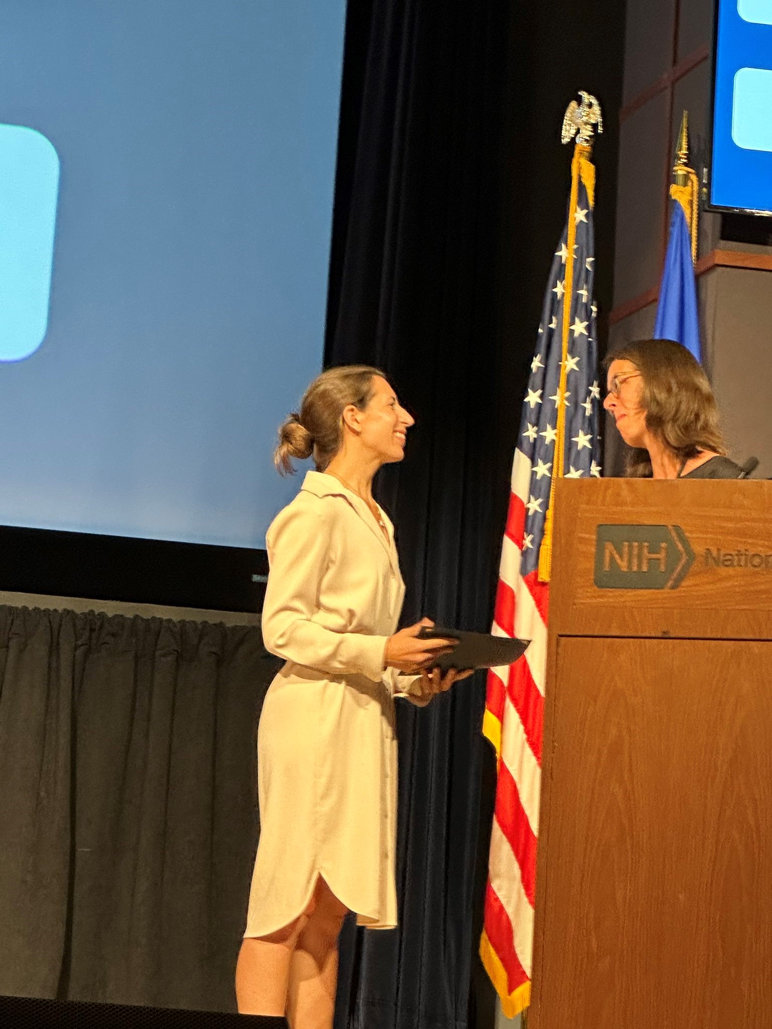 Lana Grasser stands on a stage to receive her scientific honors award at the Association for Cognitive Bias Modification. 