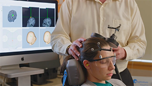 Female patient receiving transcranial magnetic stimulation on her brain from male doctor