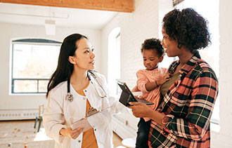 Health care provider talking with a parent who is holding a toddler.
