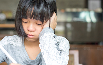 Young, upset girl sitting down and writing.