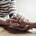 a pair of hands holds another person's hand in a gesture of comfort