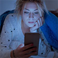 photo of teen girl propped on elbows, looking at a phone