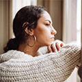 a young woman looks pensively out a window