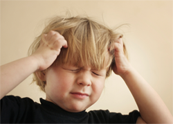 young boy holds hands to head, angry, frustrated