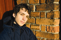 teenage boy in front of brick wall