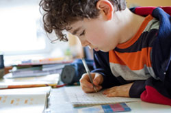 young boy writing in booklet