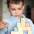 a young boy stacks wooden alphabet blocks