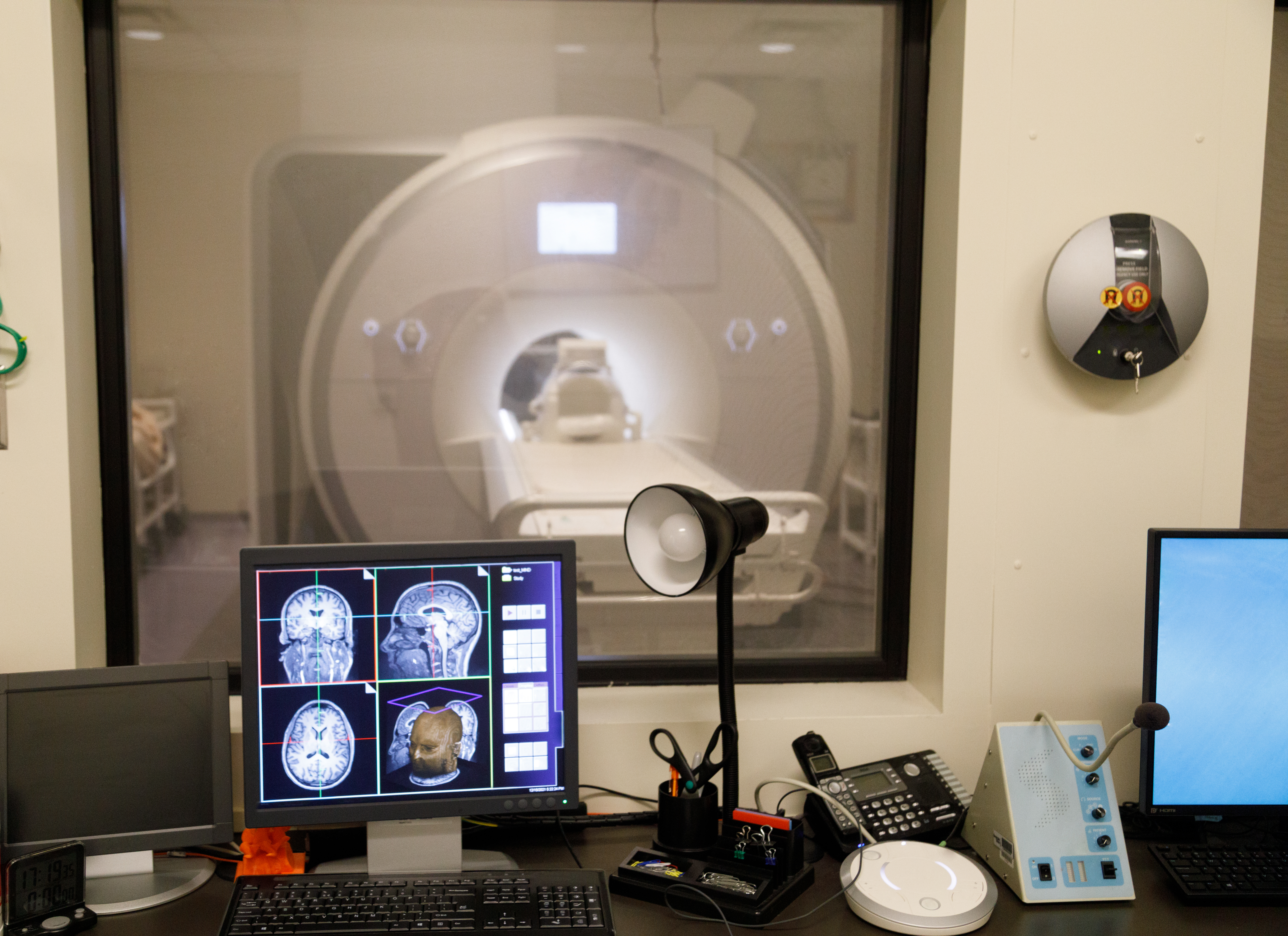 An image showing an FMRI machine with computer screens showing brain images. Credit: iStock/patrickheagney.