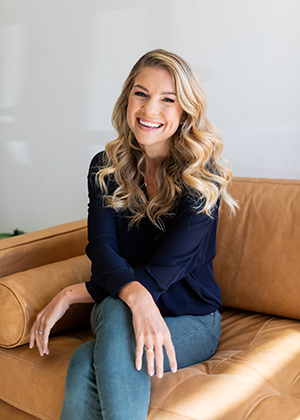 Kristina Saffran sitting on a chair smiling. 