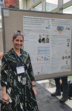 Dr. Melissa Brotman standing in front of the Neuroscience and Novel Therapeutics Unit poster at the NIMH 75th Anniversary “The Evolution of Mental Health Research” event. 