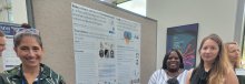 Dr. Melissa Brotman, Dr. Jamell White, and Dr. Simone Haller standing in front of the Neuroscience and Novel Therapeutics Unit poster at the NIMH 75th anniversary event. 