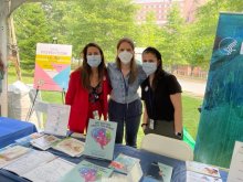 Lana Grasser, Lauren Henry, and team members standing behind a table at the NIH Safety, Health and Wellness Day. Standing next to a poster with “Suicide Prevention LGBTQ Youth.”